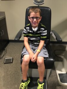 Child with glasses sitting in exam chair